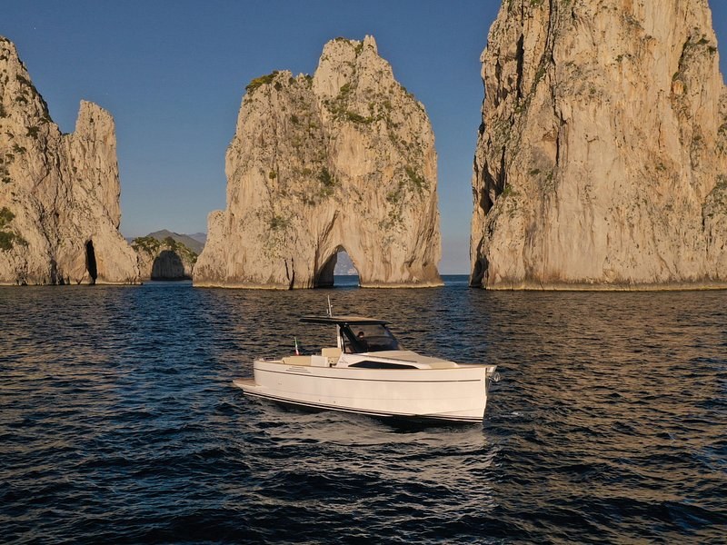 A small boat beside the Faraglioni stacks of Capri