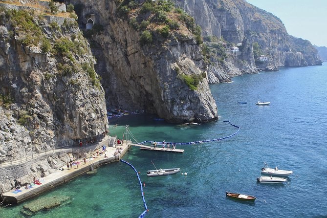 Small boats moored below sheer cliffs on the Amalfi Coast