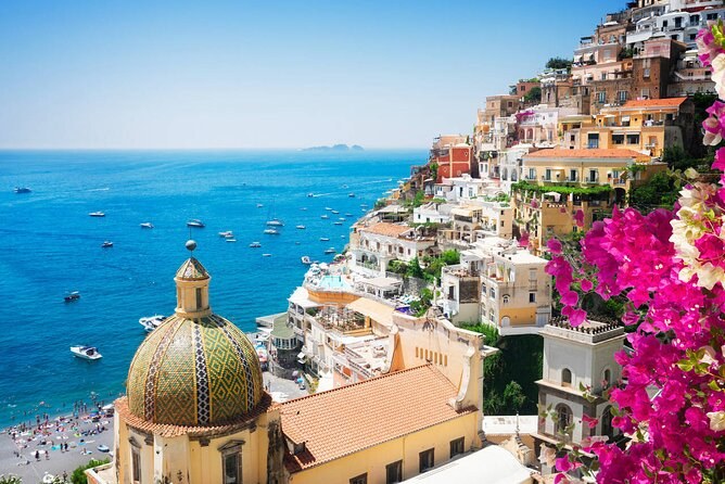 The tiled dome of Santa Maria Assunta behind bougainvillea, the sea beyond
