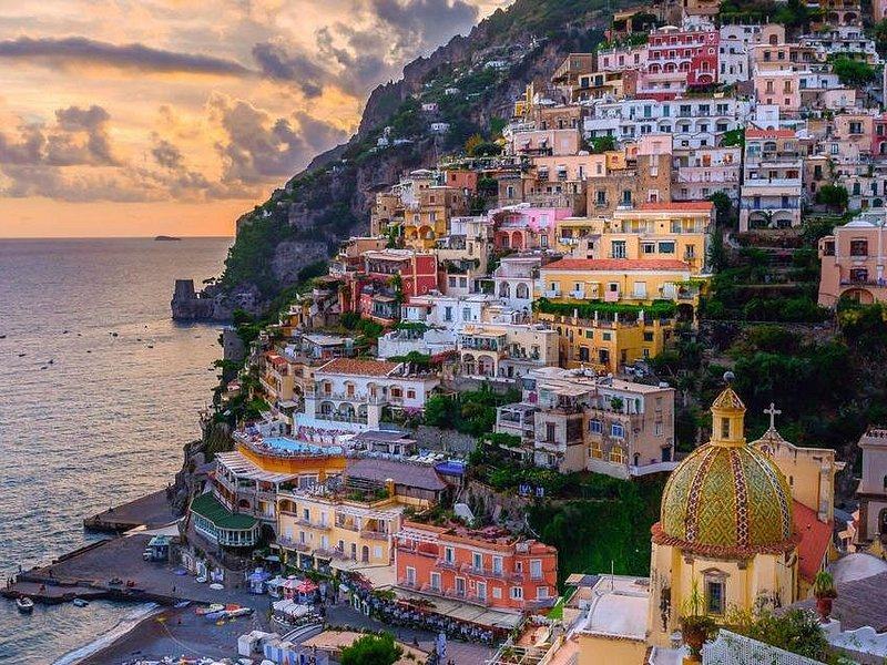 Positano at sunset, the majolica dome of Santa Maria Assunta below the stacked houses